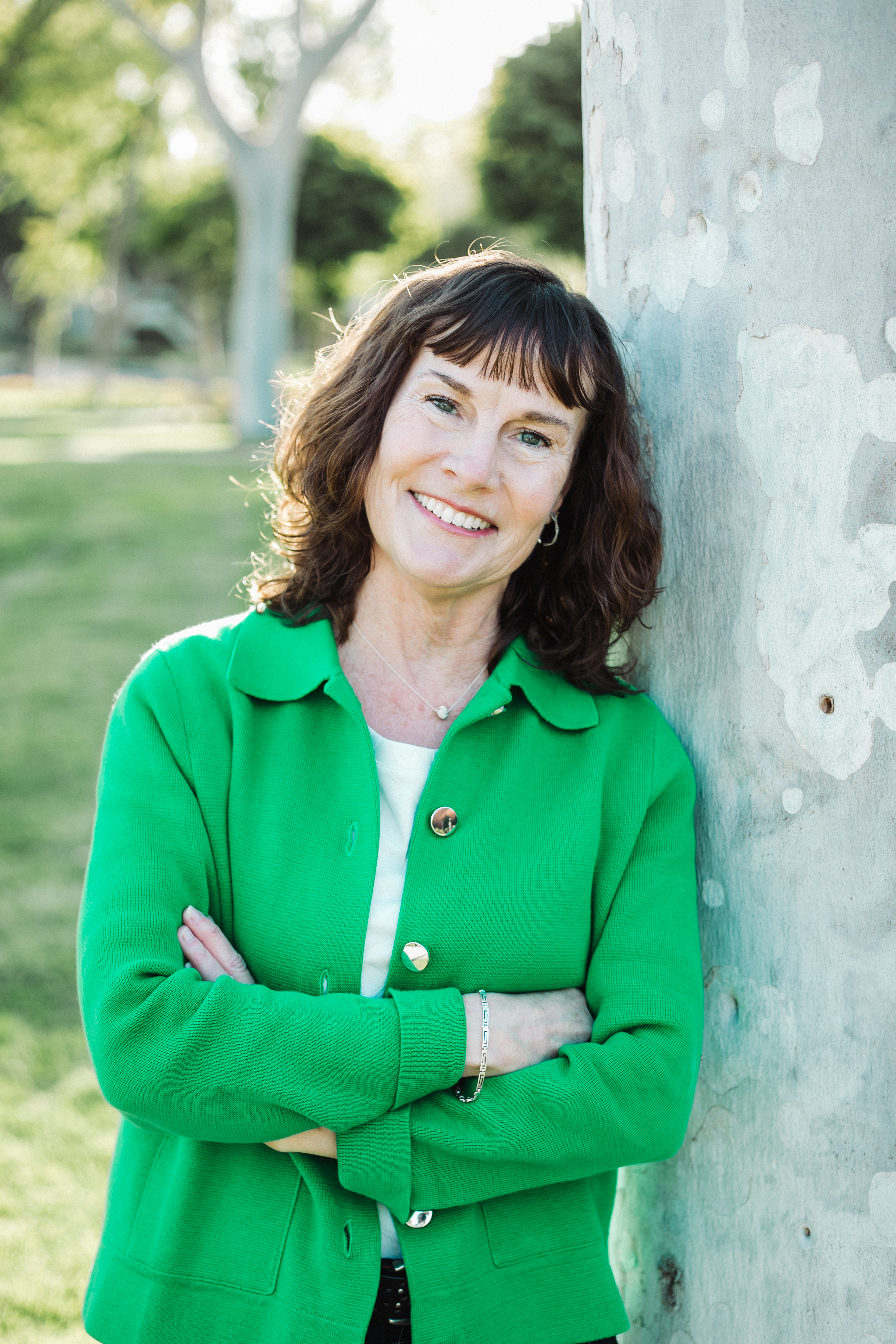 Kathleen A. Brown smiling beside a tree, wearing a green jacket